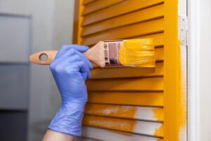 Closeup female hand in purple rubber glove with paintbrush paint