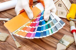 Hands holds color swatches book over table with work tools and m